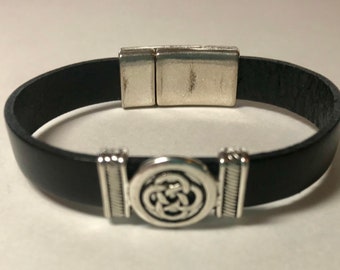 May include: A black leather bracelet with a silver magnetic clasp and a silver Celtic knot design.