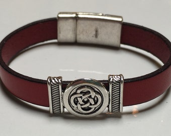 May include: A red leather bracelet with a silver magnetic clasp and a silver Celtic knot design.