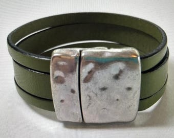 May include: A green leather wrap bracelet with a silver metal clasp. The clasp has a textured, hammered finish.