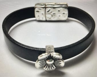 May include: A black leather bracelet with a silver magnetic clasp and a silver flower charm.