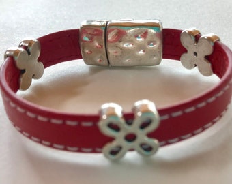 May include: A red leather bracelet with a silver magnetic clasp and silver flower charms.