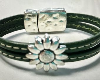 May include: A green leather bracelet with a silver sunflower charm and a magnetic clasp.
