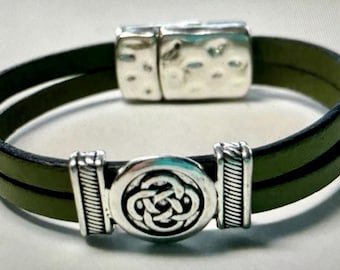 May include: A green leather bracelet with a silver Celtic knot design and a magnetic clasp.