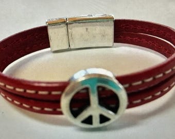 May include: Red leather bracelet with a silver magnetic clasp and a silver peace sign charm.