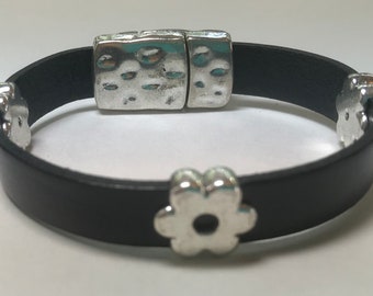 May include: A black leather bracelet with a silver magnetic clasp and silver flower accents.