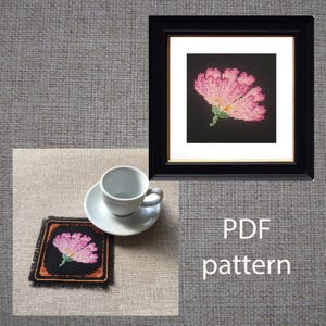 May include: A framed cross-stitch of a pink flower with a black background, a matching coaster, and a teacup and saucer. The text "PDF pattern" is visible in white.