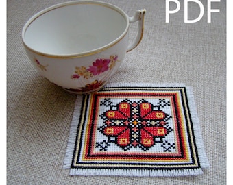 May include: A red, yellow, and black cross-stitch coaster with a floral design. The coaster is on a beige fabric surface. PDF.