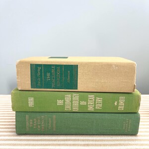 May include: Three stacked vintage books. The top book is beige with a green title label that reads "The Peaceable Kingdom." The middle book is green with "The Columbia Anthology of American Poetry." The bottom book is green with "The Year of the French."