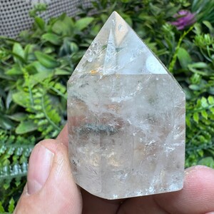 Pode incluir: Uma ponta de cristal de quartzo transparente com uma aparência natural e nublada. O cristal é facetado e tem uma ponta pontiaguda. Tem aproximadamente 5 cm de altura.