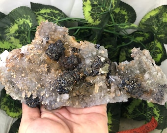 May include: A cluster of quartz crystals with dark, metallic pyrite inclusions. The quartz is clear and crystalline, with a light brown hue in some areas. The pyrite appears as dark, irregular masses throughout the quartz formation.