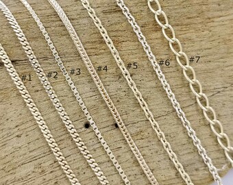 May include: Seven different silver chains laid out on a wooden surface. The chains are numbered 1 through 7.