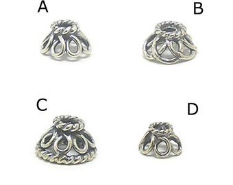 May include: Four silver metal bead caps with intricate designs. The caps are in different sizes and have a delicate, ornate look.