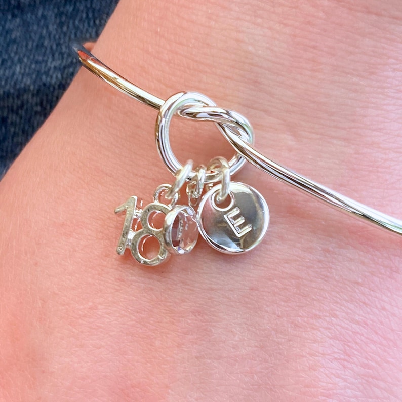 18th birthday gift bracelet for girls, being worn to show how the bracelet fits onto the 18 year old's wrist and shows the way the crystal, initial and number charm naturally hang from the knot of the bracelet.