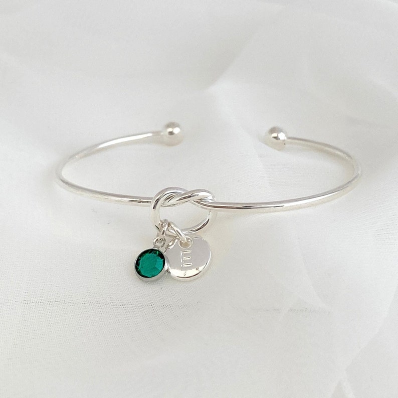 Personalised Silver Knot Bracelet with Initial and Birthstone Crystal: Meaningful Jewellery Gift for Women. This beautiful silver plated, open cuff, friendship knot bracelet makes a perfect gift for family or friend. It can be personalised with a birthstone crystal charm and a silver-plated initial letter charm of your choice.