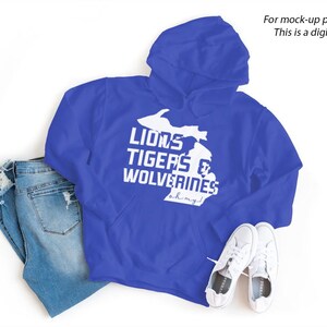 May include: A royal blue hoodie with a white outline of the state of Michigan and the text "Lions Tigers & Wolverines" with the words "ah my god" underneath.