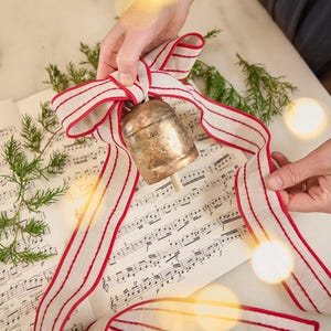 Campana festiva con cinta roja, dije de metal moldeado a mano, elegante decoración navideña hecha a mano.