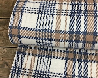 May include: A roll of fabric with a classic plaid pattern. The design features a combination of white, navy blue, and brown hues. The fabric is likely suitable for apparel or home decor projects.