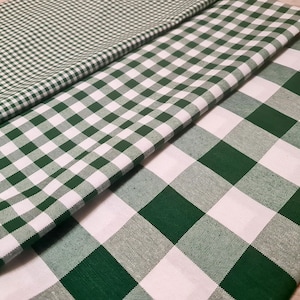 May include: Three different green and white checkered fabrics are layered on top of each other. The patterns vary in size, from small to large checks. The fabrics are folded and appear to be made of cotton or a similar material.