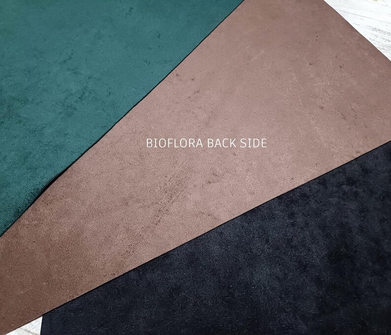 May include: A close-up of three fabric samples in green, brown, and black. The green is a dark, forest hue, the brown is a muted tan, and the black is a deep tone. The text "BIOFLORA BACK SIDE" is printed in white across the image.