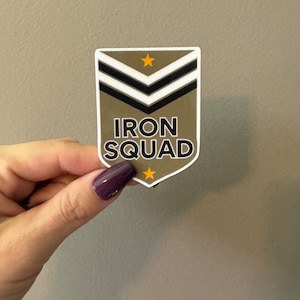 May include: A green and white sticker with black text that says "IRON SQUAD". The sticker has a chevron design with three stripes and two gold stars.