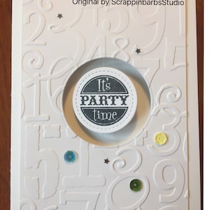 May include: White card with a black circle in the center that says "It's Party Time". The card is decorated with embossed numbers and sequins.