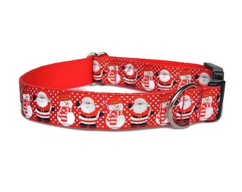 May include: A red dog collar with a repeating pattern of Santa Claus and snowman figures. The collar has a black plastic buckle and a silver metal D-ring for leash attachment. The design features white polka dots.