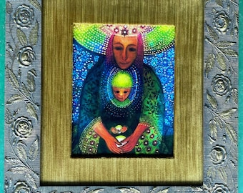 May include: A framed painting of a woman with a crown holding a child in her arms. The woman and child are surrounded by a colorful, abstract background. The frame is ornate with a gold and silver finish.