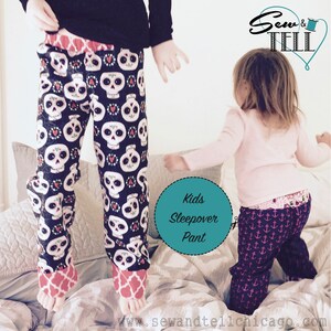 May include: Two children wearing colorful pajama pants. The girl is wearing navy blue pants with pink anchors and the boy is wearing black pants with white skulls and red hearts. The text "Kids Sleepover Pant" is on a teal circle.