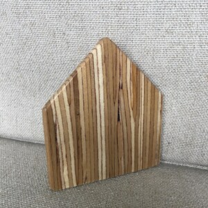 Könnte beinhalten: Eine kleine, dreieckige Holzhausform aus Sperrholz mit natürlicher Holzmaserung.