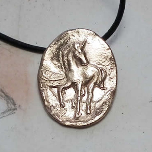 Collier-médaillon ovale  fait main en bronze ou en cuivre   représentant une  petite licorne   sur  lacet de cuir noir