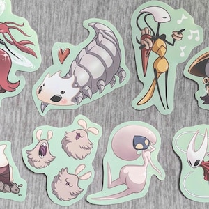 May include: A collection of die-cut stickers featuring various cartoon characters in different poses. The stickers have a light green border and are set against a gray background. The characters are in various colors, including red, white, and yellow.