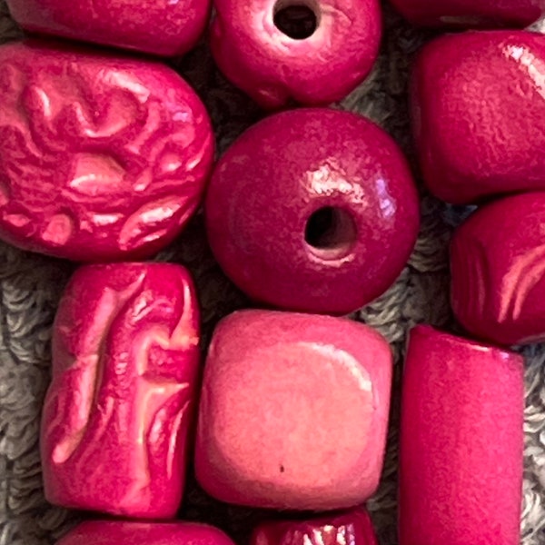 25 hand-made ceramic beads, assorted shapes in magenta.