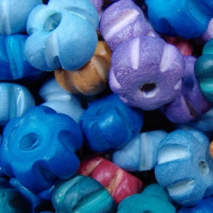 May include: A close-up of a variety of colorful wooden beads. The beads are in various shapes and sizes, including round, star-shaped, and flower-shaped. The beads are painted in shades of blue, purple, brown, and teal.