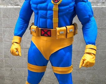Può includere: Un costume da supereroe blu e giallo. Il costume presenta un body blu con dettagli gialli, tra cui una cintura, guanti, stivali e una visiera. Il petto ha un emblema rosso e nero. Il costume è progettato per assomigliare a un personaggio dei fumetti.