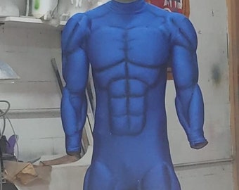 May include: A blue, muscle-toned, full-body suit on a mannequin. The suit has a silver face mask with a black design. The mannequin is standing in front of a white wall with a Marvel poster in the background.