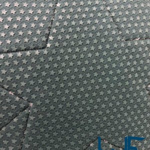 May include: Close-up of a dark teal fabric with a repeating pattern of small, raised stars. The fabric is divided into geometric sections by seams. The lower right corner features a logo with the text "WAYNE FACTORY COSTUMING STUDIO."