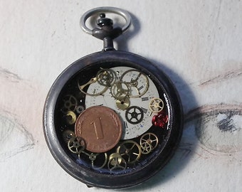 Pendentif steampunk-porte bonheur, boitier de montre gousset avec Glückpfennig,cadran, rouages inclus dans la résine, sur lacet de cuir noir