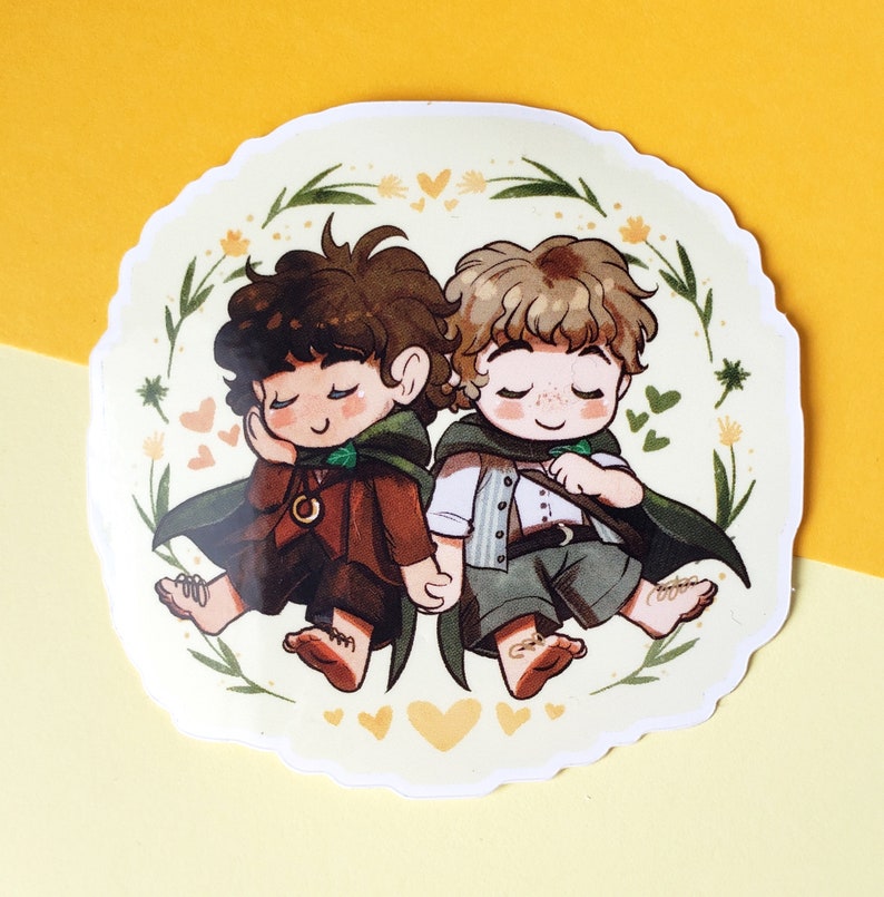 Op de afbeelding: Een sticker met twee cartoonfiguren, een met bruin haar en een groene mantel, de ander met blond haar en een groene mantel, die hand in hand staan. Ze worden omringd door gele bloemen en harten op een witte achtergrond.