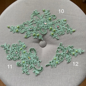 May include: Three mint green lace appliques with floral and leaf designs. Each applique is embellished with small, round, light green beads and iridescent rhinestones. The appliques are numbered 10, 11, and 12.