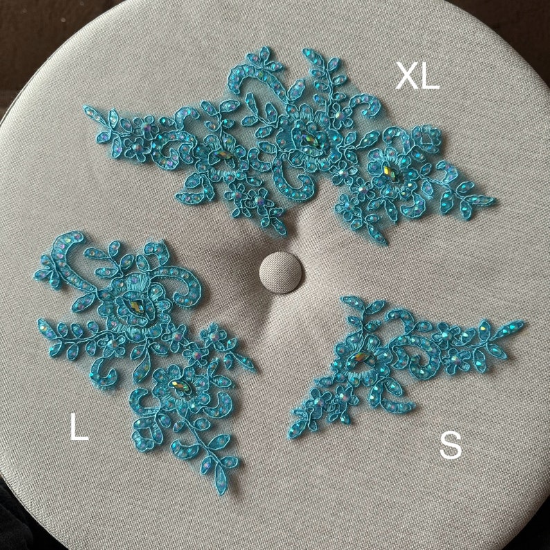 May include: Three turquoise lace appliques with rhinestones, labeled 'XL', 'L', and 'S'.