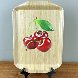 May include: A rectangular bamboo serving tray with a cherry design. The tray has a natural wood finish and features three red cherries with green leaves.