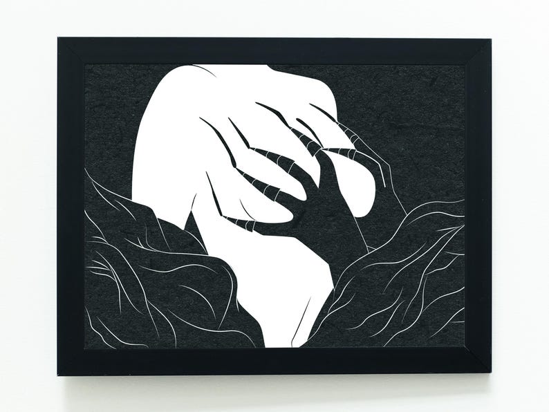 May include: Black framed art print featuring a stark, minimalist design. The artwork depicts a white form with claw-like hands reaching out from a dark, textured background. The contrast between the white and black creates a striking visual.