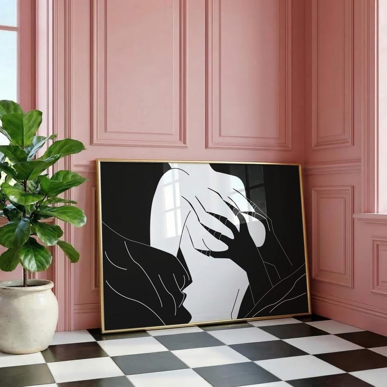 May include: A framed art print featuring a black and white abstract design. The artwork depicts a figure with hands and a face in a minimalist style. The print is displayed against a pink wall and a black and white checkered floor.