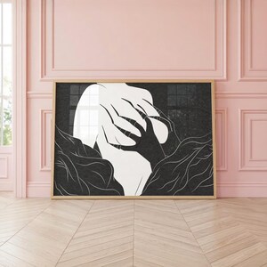 May include: Black and white abstract art print in a wooden frame. The artwork depicts a figure with hands covering the face, surrounded by stylized organic shapes. The contrast between light and dark creates a dramatic effect.