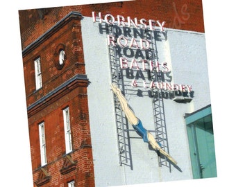 Op de afbeelding: Een wit gebouw met een rood bakstenen gebouw ernaast. Een rood neonbord met de tekst "Hornsey Road Baths & Laundry" is bevestigd aan het witte gebouw. Een duikersilhouet is op het bord geschilderd.