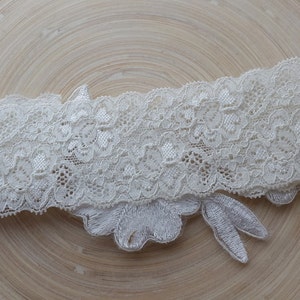 May include: White lace garter with a delicate floral design. The garter is made of soft, stretchy lace and has a comfortable fit.
