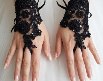 May include: A pair of black fingerless lace gloves featuring intricate floral embroidery, small black sequins, and delicate beadwork. Each glove includes a thin black ribbon tie at the wrist and a loop that secures around the middle finger.