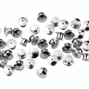 May include: A pile of silver-toned metal pin backs for crafts and jewelry making.