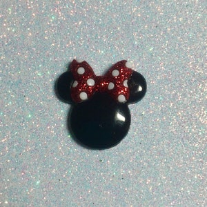 May include: A black and red glitter Minnie Mouse head with white polka dots on the bow.