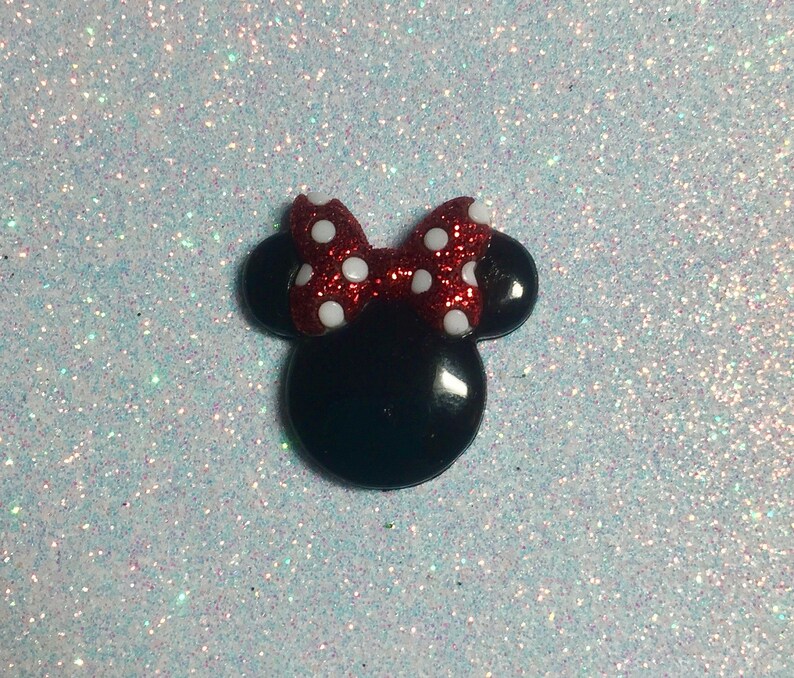 May include: A black and red glitter Minnie Mouse head with white polka dots on the bow.